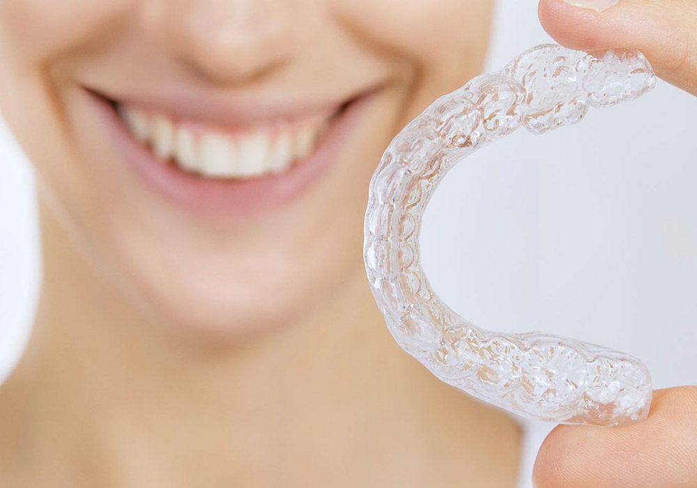 Smiling adult with Invisalign tray